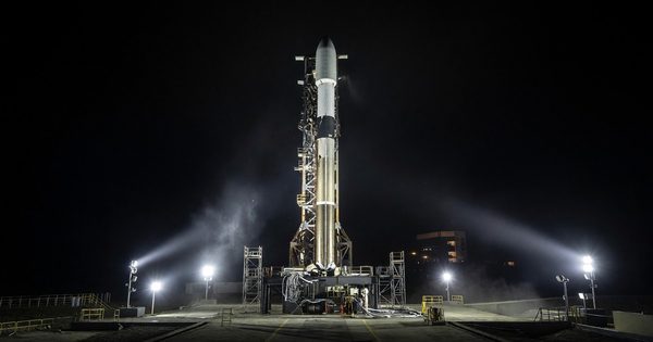 Small orbital rocket on launch pad at night with floodlights illuminating structure