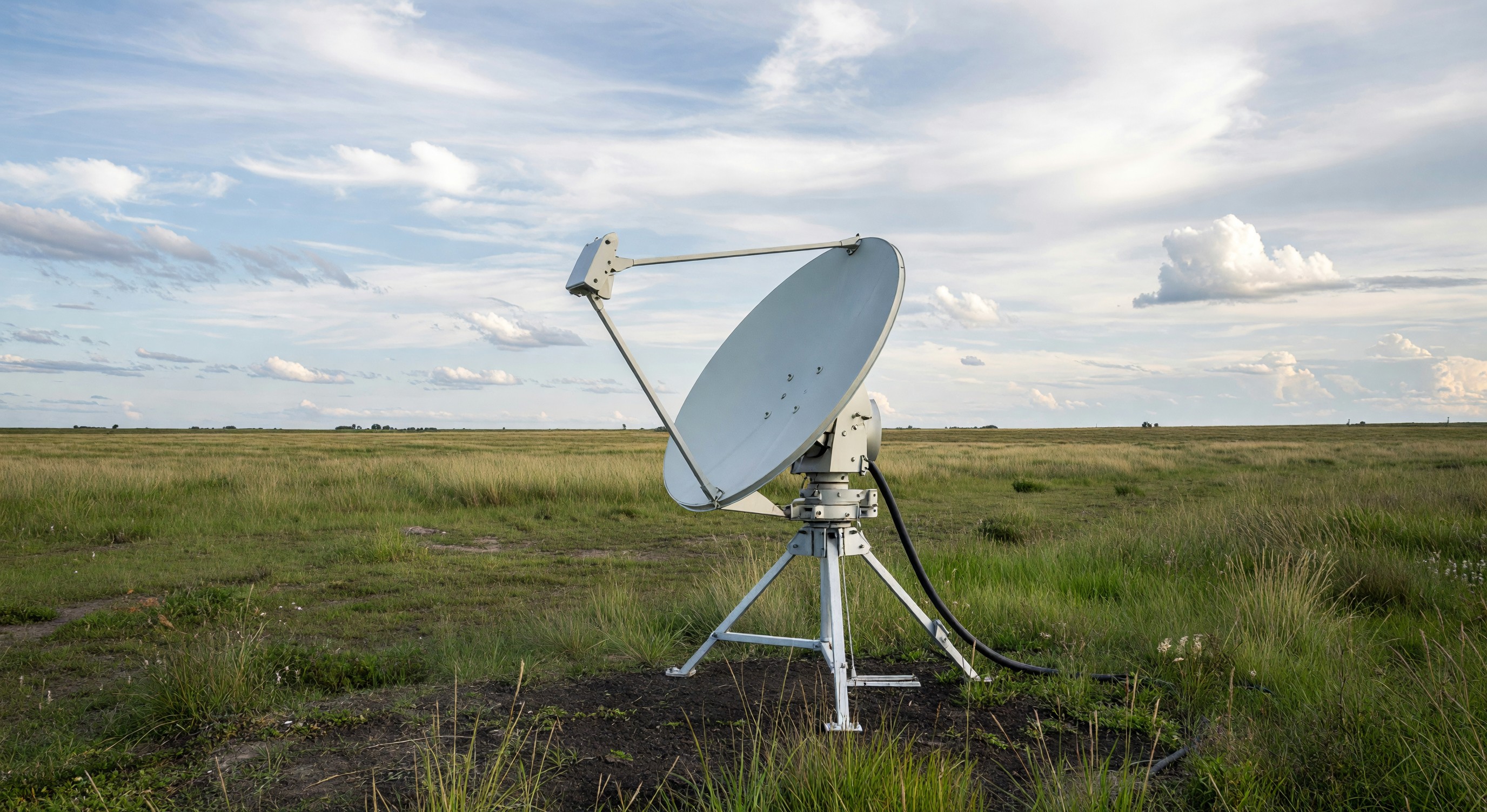 Satellite broadband terminal dish in rural field pointing at sky